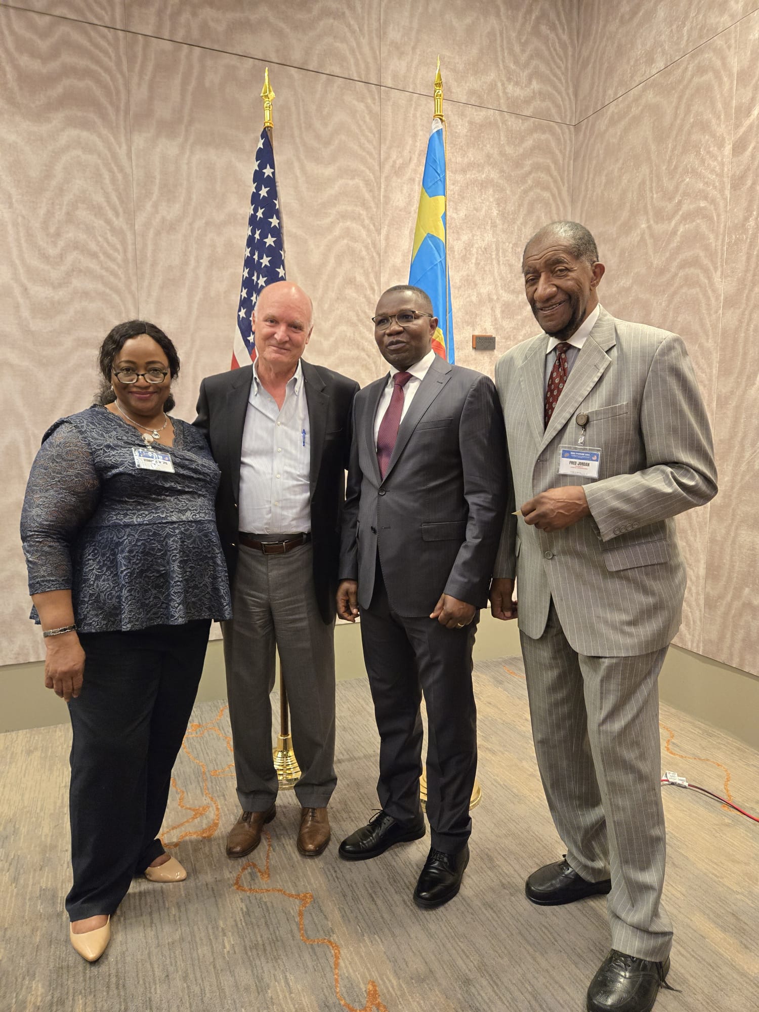 Group portrait in front of the United States and DRC flags